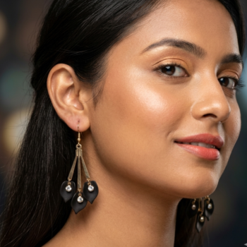 Woman wearing gold black leaf drop earrings, stylish modern jewelry look