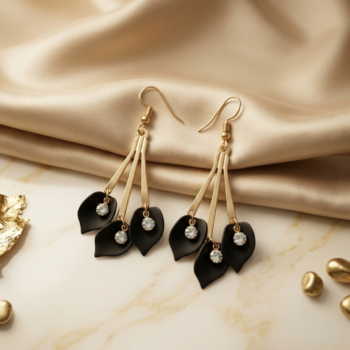 Gold and black leaf drop earrings with crystal accents on luxury fabric background