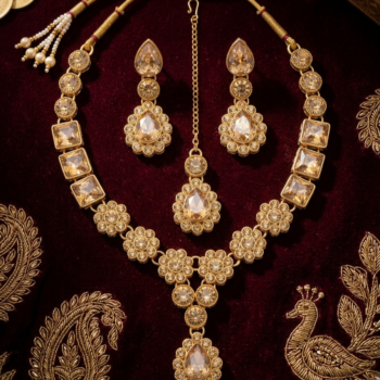 Traditional gold necklace set with champagne stones on red velvet background with matching earrings and tikka