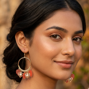 Woman wearing gold hoop earrings with heart charms and pearl drops
