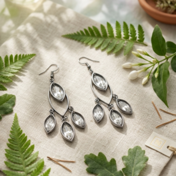 Gunmetal crystal chandelier earrings with leaf design placed on natural aesthetic background