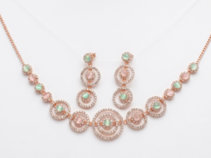 Rose gold circular necklace set with pastel green and blush stones displayed on velvet background with matching earrings