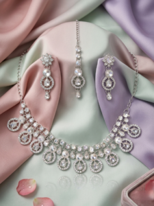Silver crystal necklace set with teardrop stones displayed on pastel fabric with earrings and maang tikka
